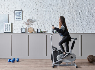 Fototapeta premium Training sportive woman at home, doing sport interior concept, decorative background and ride a bike style.