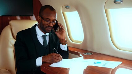 Successful entrepreneur working on his private jet, using phone - Powered by Adobe