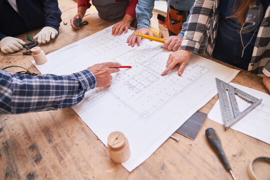 Architekten und Handwerker schauen auf Grundriss