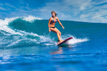 Female surfer on a blue wave at sunny day - 414098739