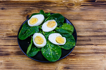 Spinach leaves and halved boiled eggs on a black plate