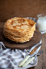 Thin fried pancakes on a plate. Traditional food for Shrovetide. Pancake with sour cream on a wooden table. Pancake day