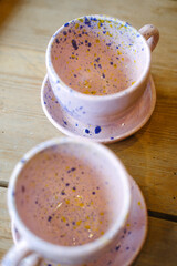 Ceramic cups on a pink saucer on a wooden table