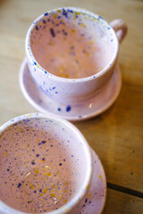 Ceramic cups on a pink saucer on a wooden table