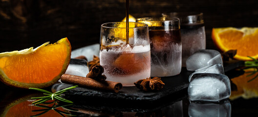 Frozen shot glass with star anise, cinnamon, orange. herb liqueur on a dark background, catering, banner, menu, recipe, place for text
