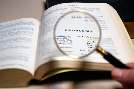 magnifying glass analysing the word"problems" on a technical test book