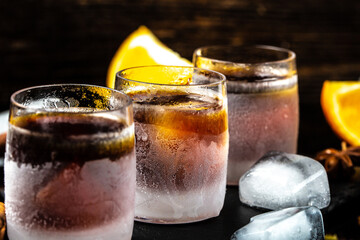 Frozen shot glass with star anise, cinnamon, orange. herb liqueur on a dark background, catering, banner, menu, recipe, place for text