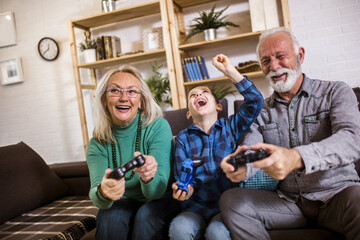 Happy grandparents playing video games with their grandson
