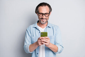 Photo of aged cheerful man happy smile browse read cellphone chat isolated over grey color...