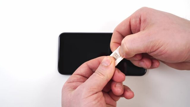 Men's hands pull out a nano sim card from the adapter mini sim card. 