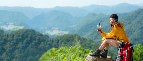 Asian women hiker or traveler with backpack adventure sitting and drinking ice coffee relax and...