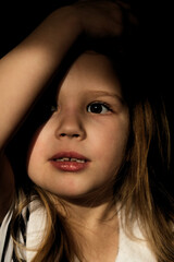 Dramatic  portrait of beautiful sad little child girl with shadow on face, close-up.  lonely in the dark. Childhood and problems of parents and children concept.