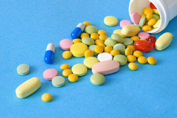 many different medicine pills, drug and capsules on blue background