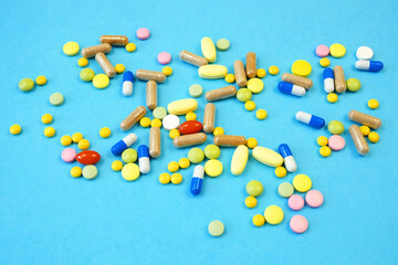 many different medicine pills, drug and capsules on blue background