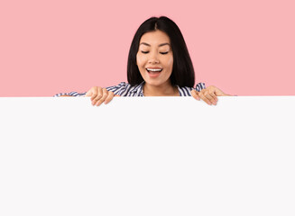 Asian woman hiding behind blank white advertising billboard