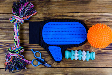 Pet slicker brushes, claw clipper and toys on a wooden background. Top view