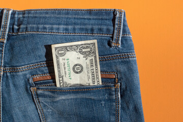One dollar bill on jeans pocket isolated on yellow background. Payday, financial insolvency, economic crisis concept. Banner, copy space