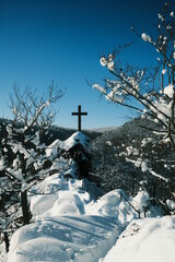 Gipfelkreuz Ilsestein im Winter mit blauem Himmel, Hochformat