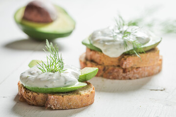 Closeup of sandwich with avocado, tzatziki sauce and dill