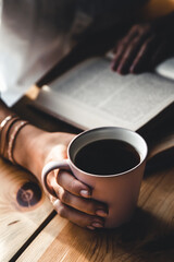 Woman in the morning drinks coffee and reads old book in a white shirt. Education, drink. manicure