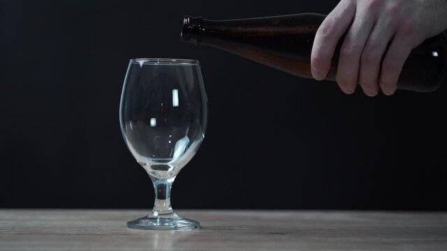 man pours beer into a glass from a glass bottle
