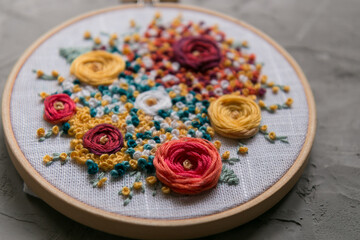 Floral embroidery on a light convoy and a skein of thread on a gray concrete background 