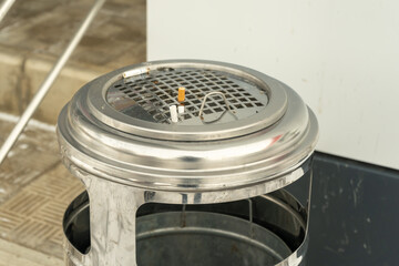 Metal bin for mixed waste and cigarette butts at the entrance to the building.