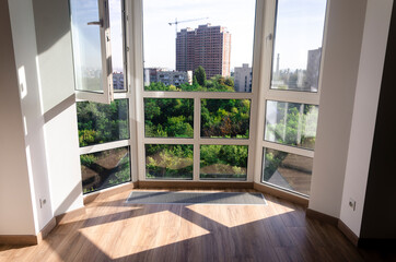 Panoramic window. Underfloor heater grill. Sharp shadows from the panoramic window frame on the wooden floor