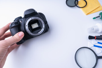 Photographer's hand holding dslr camera, camera cleaning accessories on white background