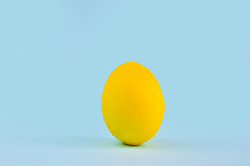 One yellow egg on a blue background. Copy of the space. Easter. Minimalism