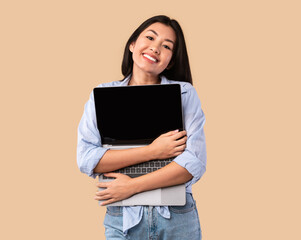 Excited asian woman hugging personal computer at studio