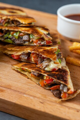 Mexican quesadilla with meat, cheese and peppers on wooden table.