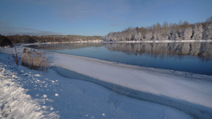 Winter landscape: the Burnaya river flows into Lake Ladoga, trees covered with hoarfrost, panoramic view