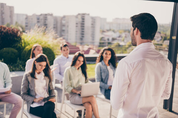 Back rear spine view photo of young confident bossy man businessman having meeting with colleagues outside outdoors