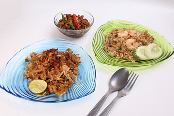 Stair fried flat rice noodles pad thai rice with prawn seafood cucumber slice garnish basil minced chicken spicy on glass color glass plate and bowl on white background