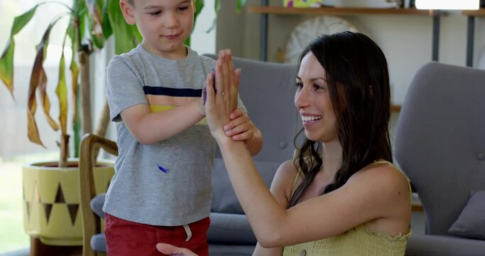 Mother and young son get messy in house with paint - home made arts and crafts