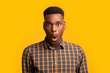 Fototapeta premium Portrait Of Surprised African American Guy Opened Mouth In Amazement, Yellow Background