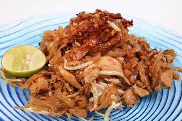 Thai style stair fried flat rice noodles pad thai on a blue glass triangular plate