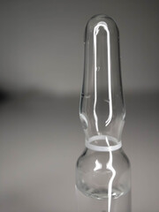One glass ampoule on a light white background close up