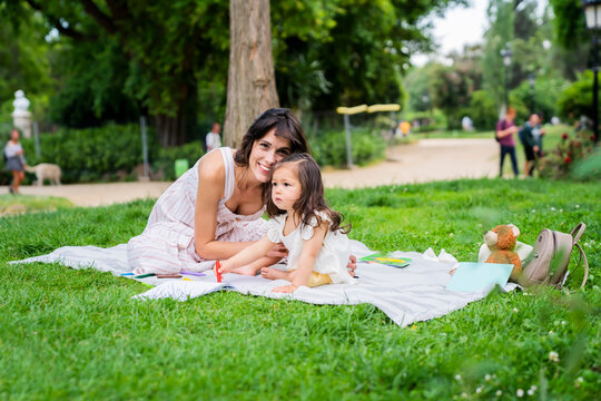 Young woman sitting on lawn and embracing child