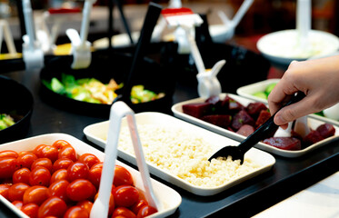 Hand holding spoon to scoop boiled Job's tears at salad bar. Salad bar buffet at the restaurant. Salad bar buffet for lunch or dinner. Healthy food. Catering food. Banquet service. Vegetarian food.