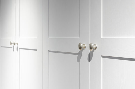 Furniture fittings. Metallic silver door handles with sharp shadows on the white facade