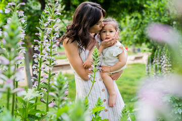 Tender mother kissing little child in hands