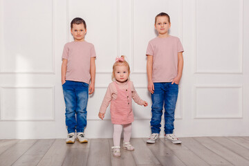 three happy children in pink T-shirts. girl and two boys in full height