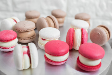 cooking, confectionery and baking concept - colorful red, white and caramel macarons on table