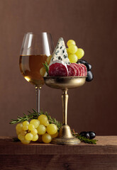 Glass of wine with snacks on a brown background.