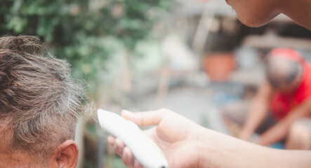 Hairdresser making stylish haircut for a handsome old man. During coronavirus pandemic restrictions
