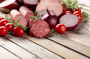 Food tray with delicious salami, ham, fresh sausages, tomato, and rosemary.