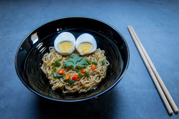 Instant noodles with boiled eggs sprinkled with vegetables and herbs.