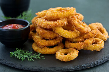 Homemade crunchy fried onion rings with tomato sauce